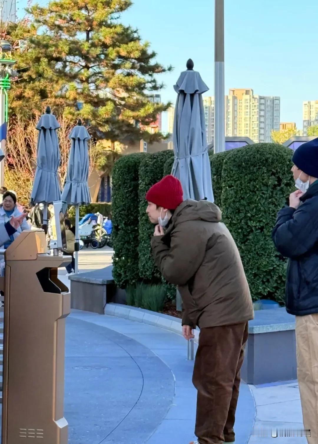 董子健带着女儿现身北京环球影城，戴着红色帽子，穿着棉服，侧颜看着肤色很白，鼻梁特