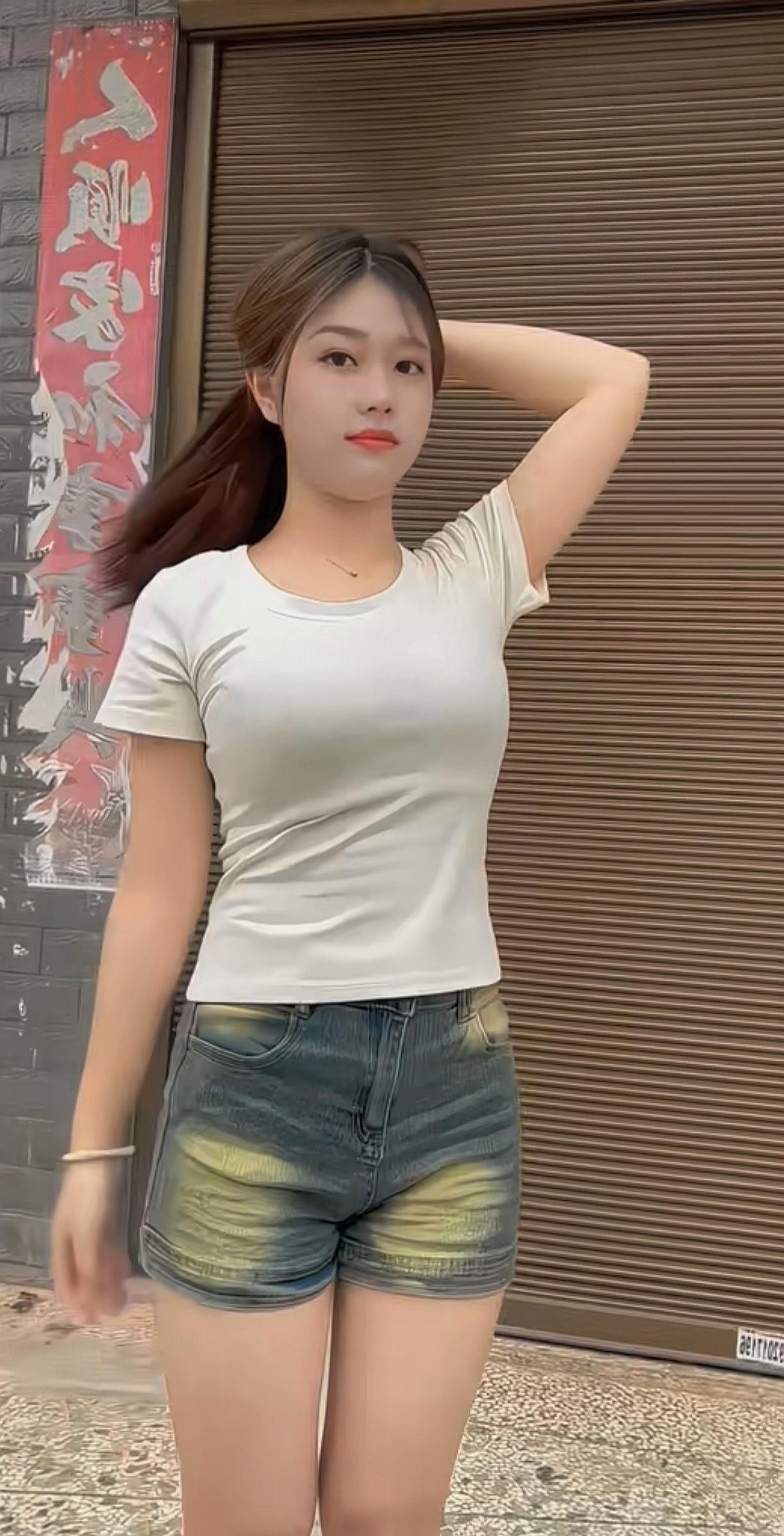 一个穿白色T恤和牛仔短裤的女孩站在门前。