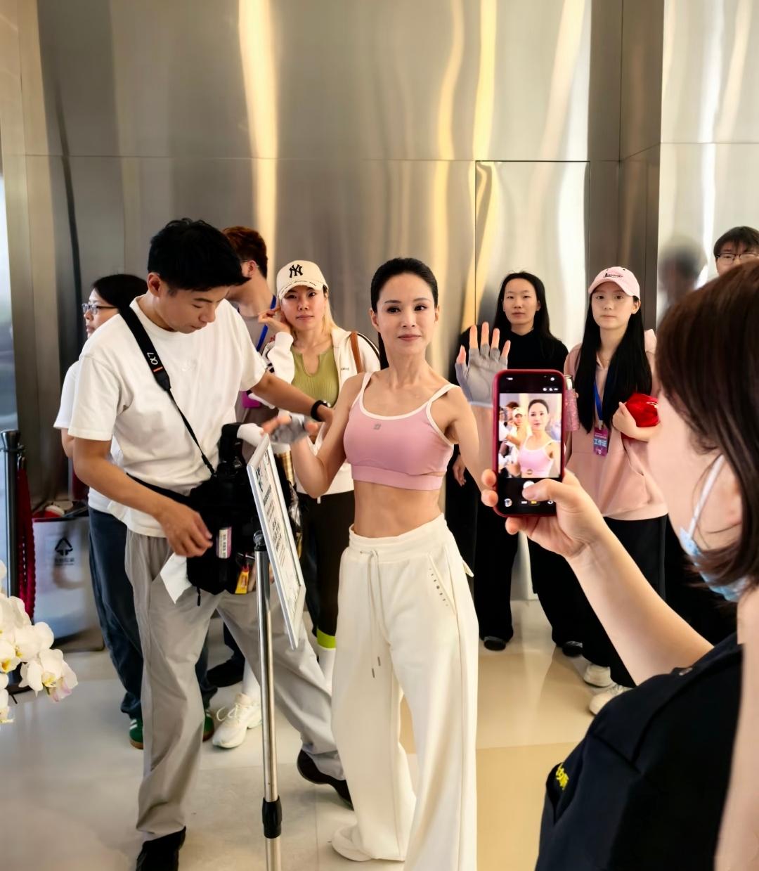 李若彤在苏州商场和粉丝互动拍照，她一件粉色小背心，露出马甲线小蛮腰，梳着高高的马