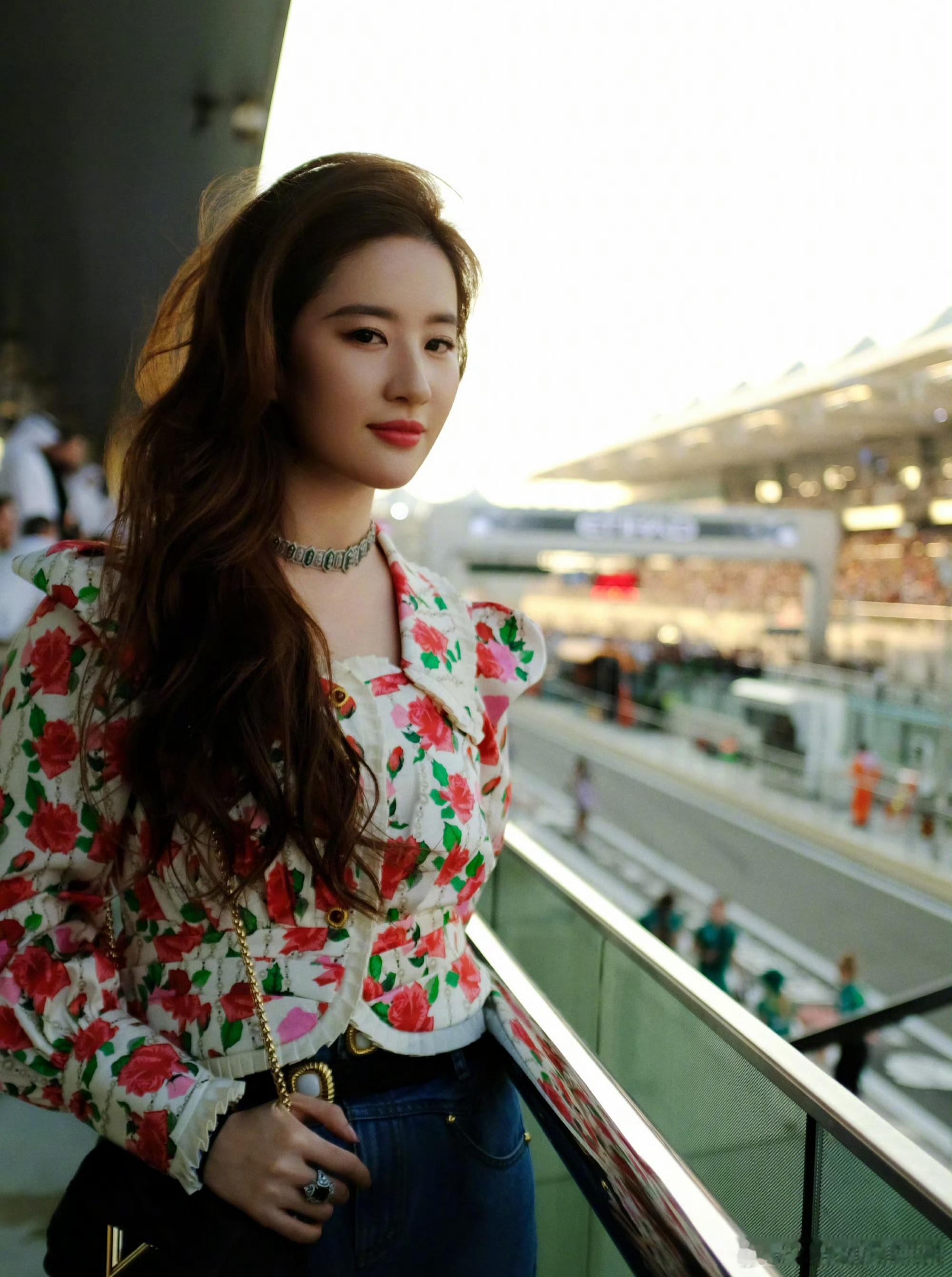 刘亦菲一身白底玫瑰印花短款外套，搭配同系列抹胸内搭，明艳的红玫瑰与绿叶印花在米白