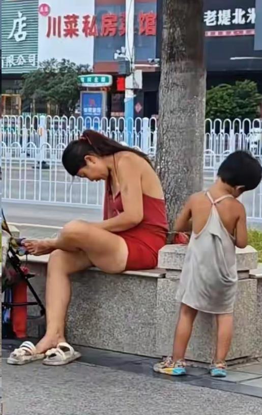 35℃高温，徐州街头的绿化树下，一对母女已经住了半个月。母亲穿着红色连衣裙，头