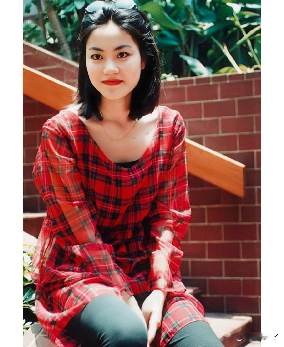 这是王菲年轻时的一张留影旧照，拍摄于一九九一年。彼时王菲二十二岁，身穿红色格子衣
