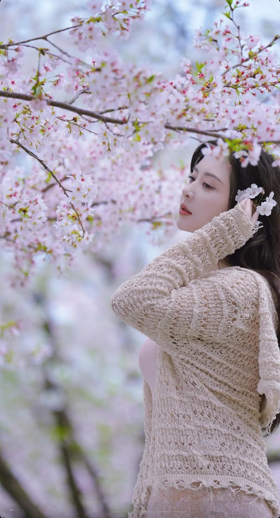 樱花树下，少女轻抚发梢，温柔如梦。