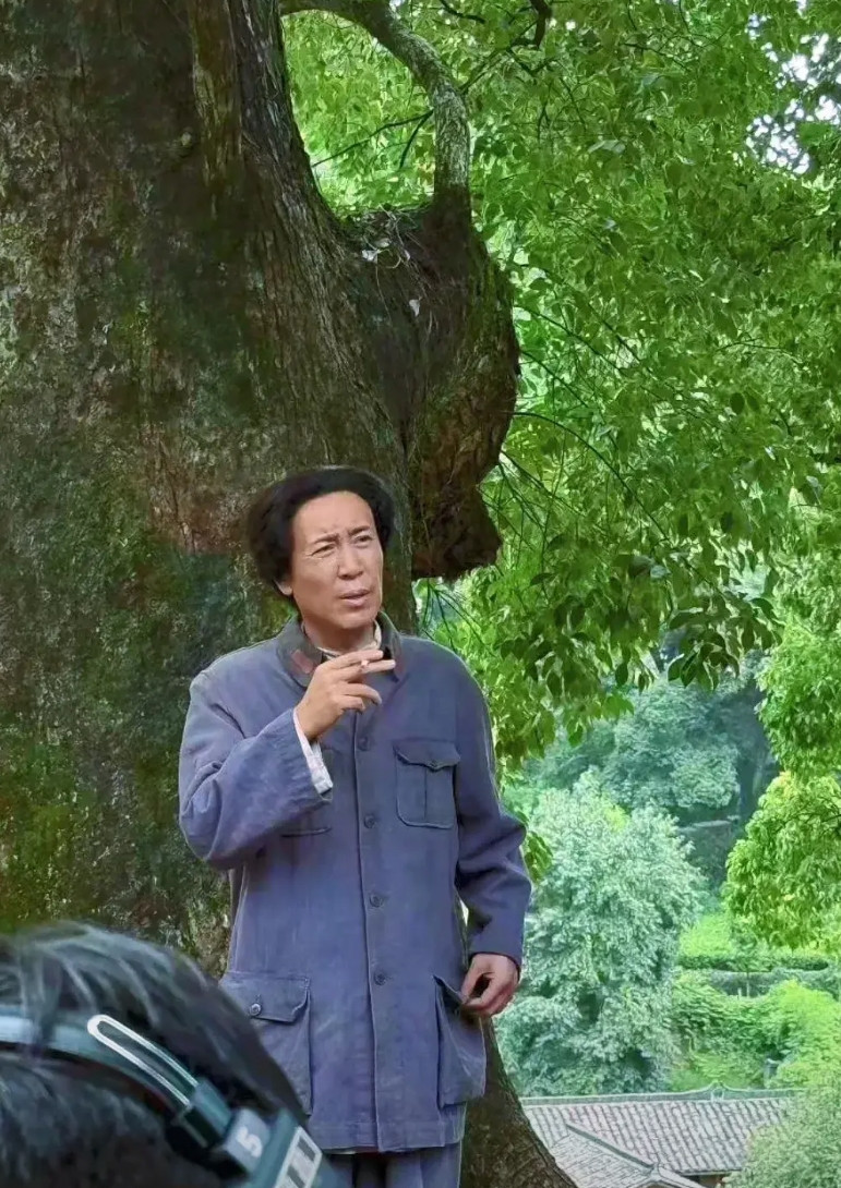《伟大的长征》剧组，于和伟穿着旧军装，靠在树上皱着眉头，一口一口抽烟，已经有了影