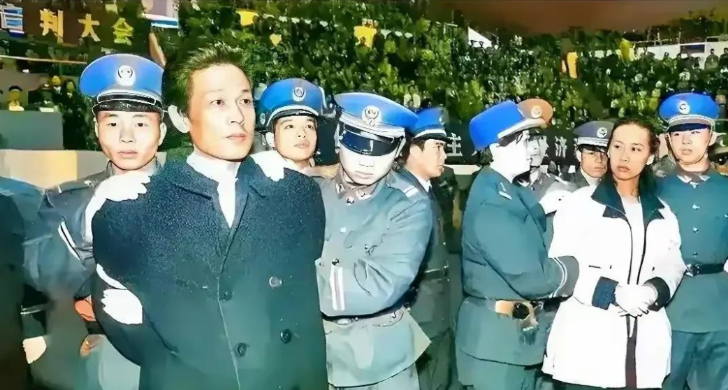 这张照片拍摄于1995年12月28日，记录了深圳“王建业、史燕青贪腐案”公审宣判大会的现场。图中被法