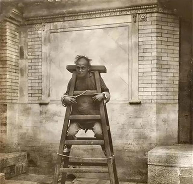 清朝时期，一个仆人因为犯了错，受到主人的惩罚。照片中这个男子坐在一架木梯子上面，