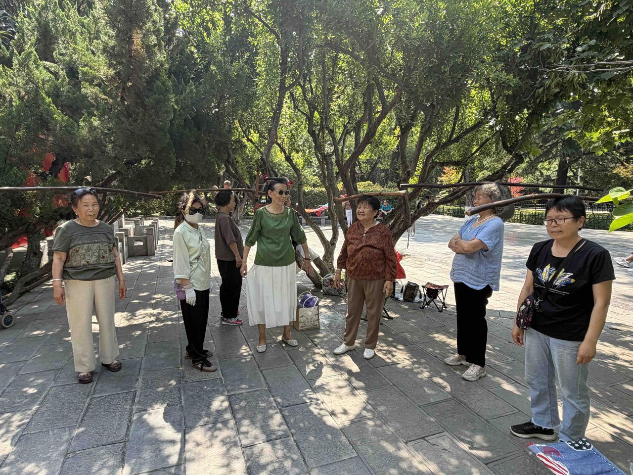 今天上午，我逛西安莲湖公园，在北门东侧看到，一群大妈，人人头上顶着一根木棍，还有