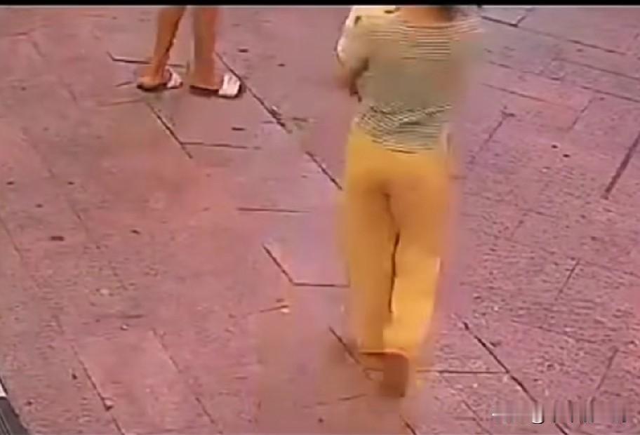 街上，一女子抱着孩子，正走着，在一个小斜坡上，不慎滑了一下，摔倒了，她把孩子抱在