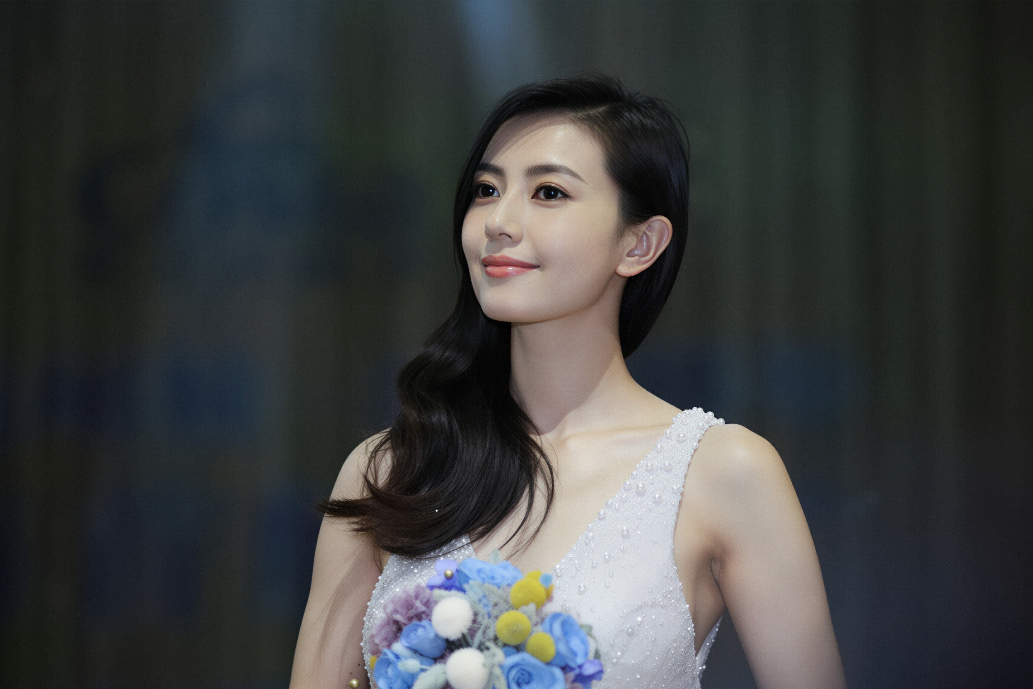 高圆圆珍珠白纱裙衬得她气质温婉又灵动，手捧蓝紫花束，眉眼间尽是松弛优雅，瞬间治