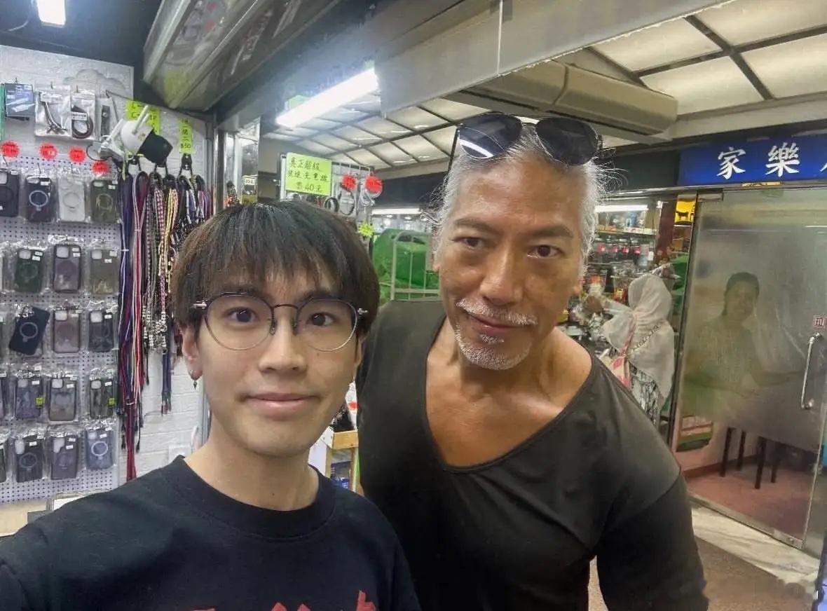 62岁张耀扬在香港逛杂货市场，他穿着V领T恤，墨镜戴在头上，一副大佬的形象，看起