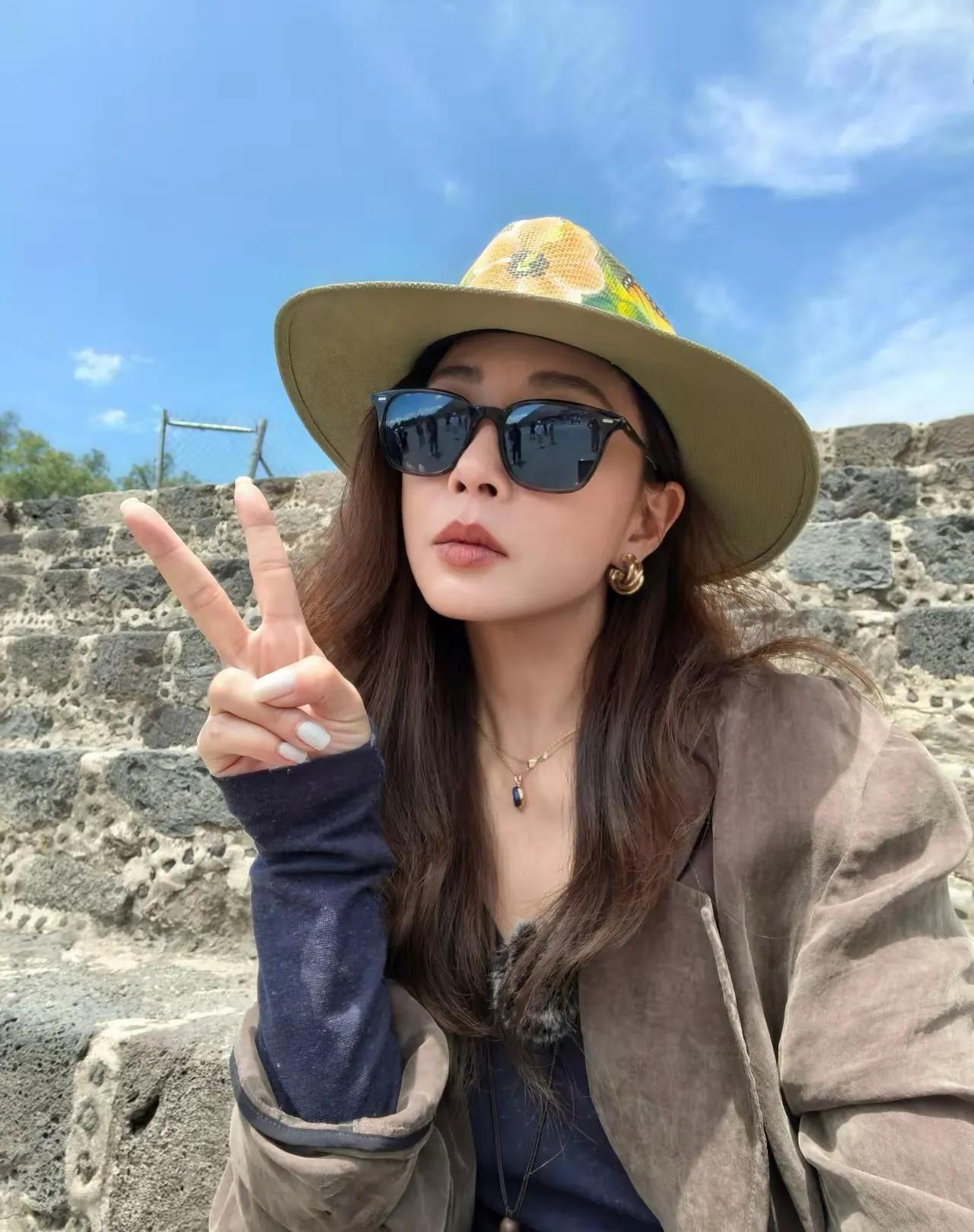 殷桃旅行随拍太有味道！长款咖色风衣搭配阔腿牛仔裤，配上特色彩绘草帽，松弛感直接