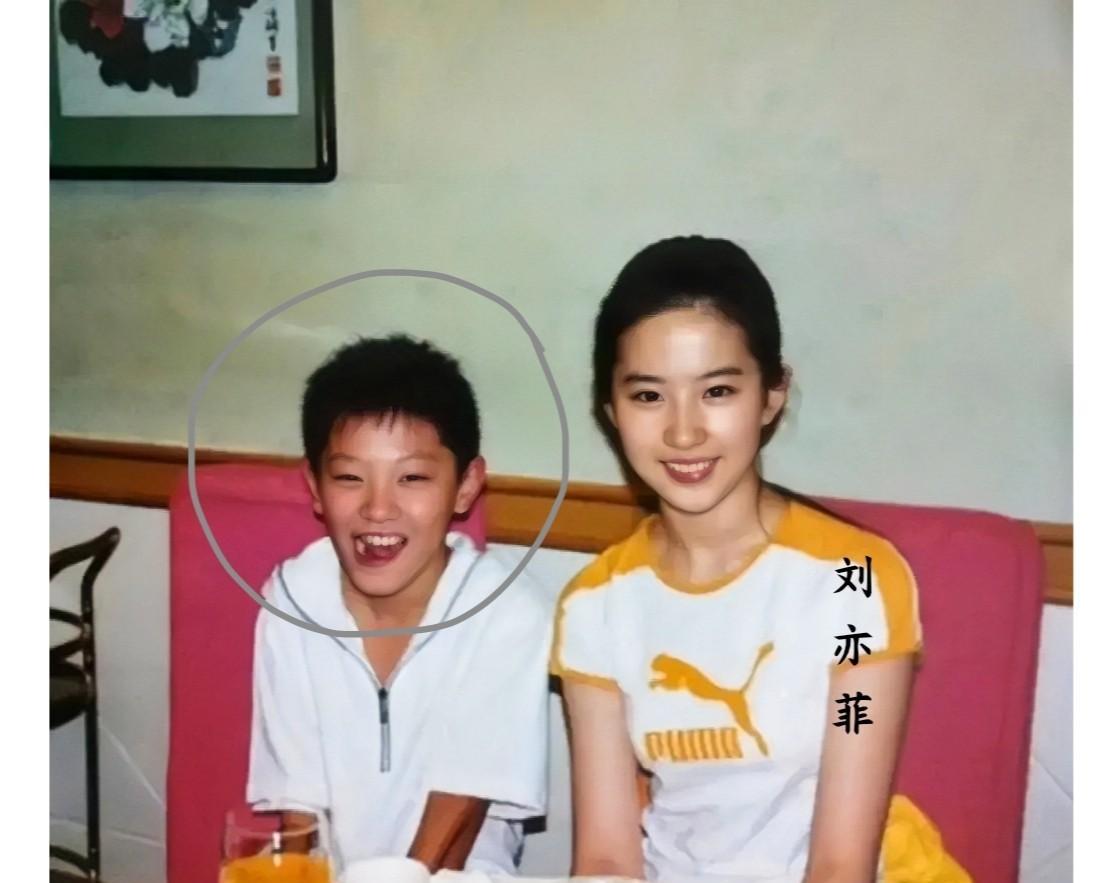 这张照片记录下了刘亦菲与一个小男孩在2003年餐桌上的美好瞬间，那时候刘亦菲十六
