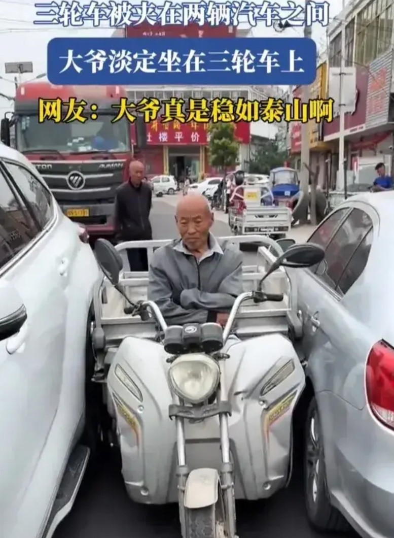 三轮车被夹在中间，大爷双手插腰，淡定的坐着，责任确实在大爷，但是他没钱赔，三方僵