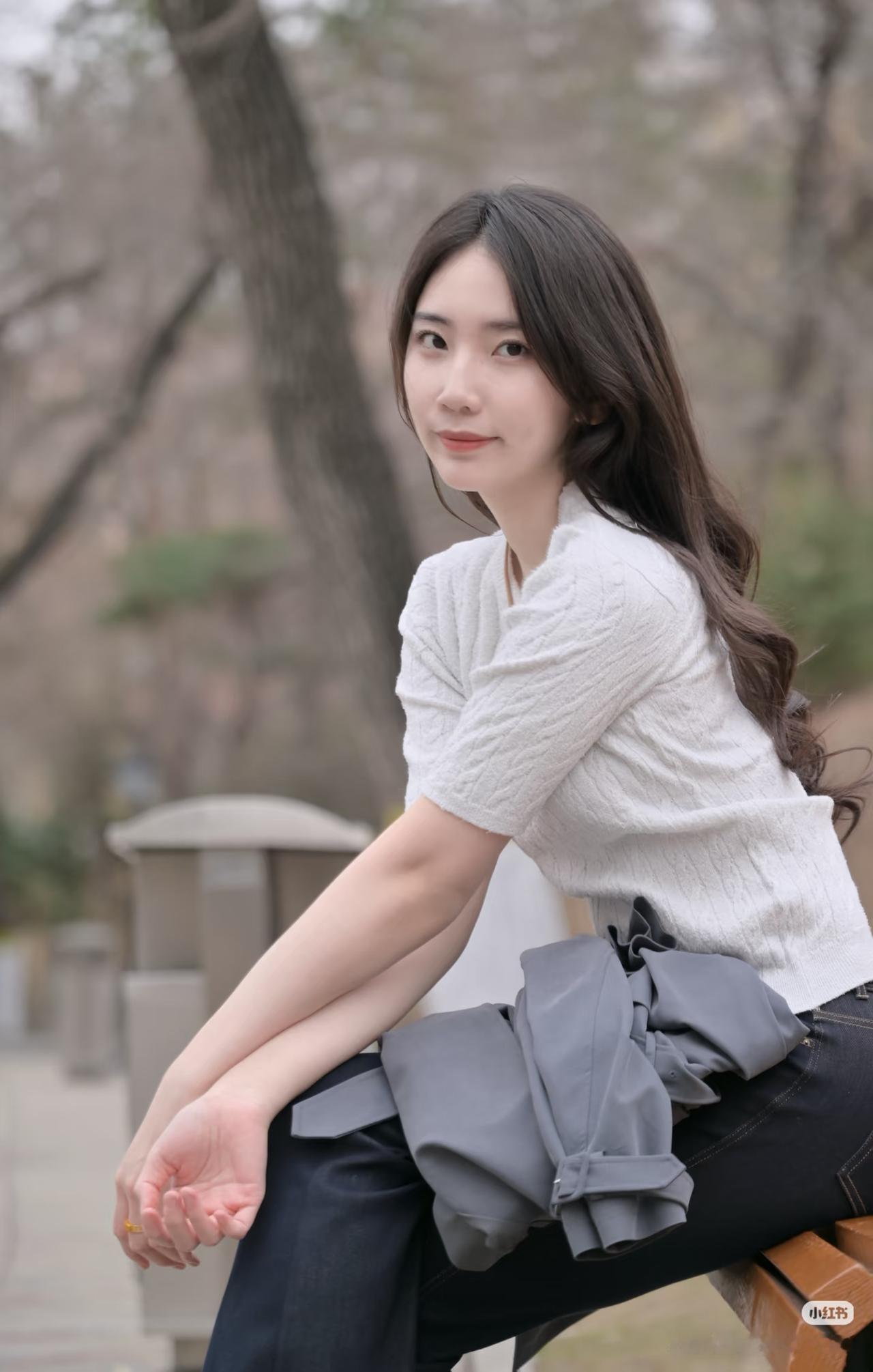 秋日暖阳下，温柔少女倚树而坐，静享美好时光。