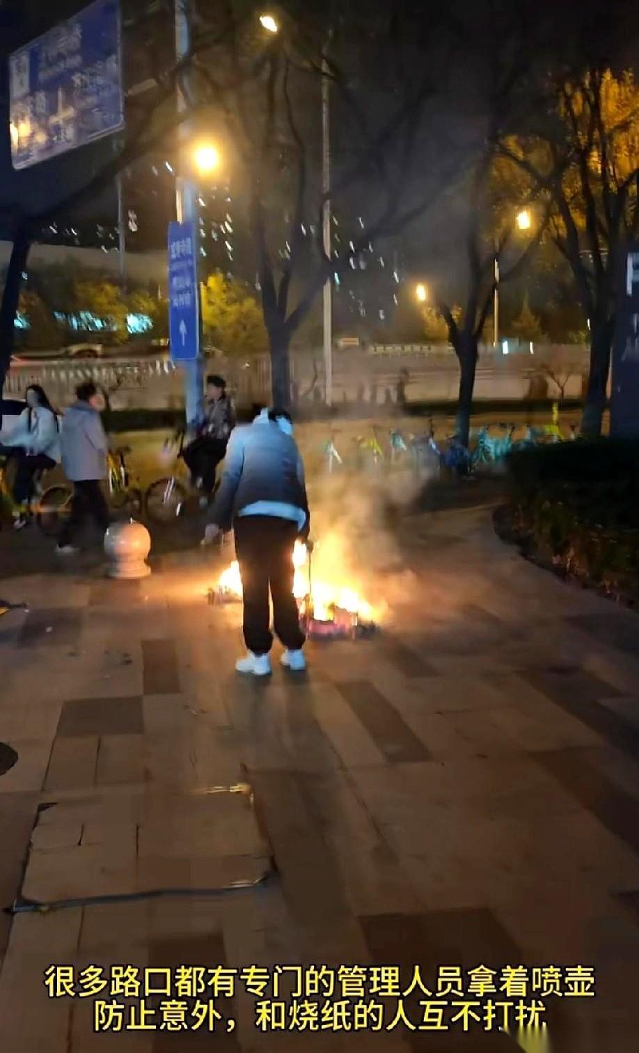 马路牙子上，一个火圈，一个人，一沓纸。不远处，一个大哥抱着灭火器，静静地看着。