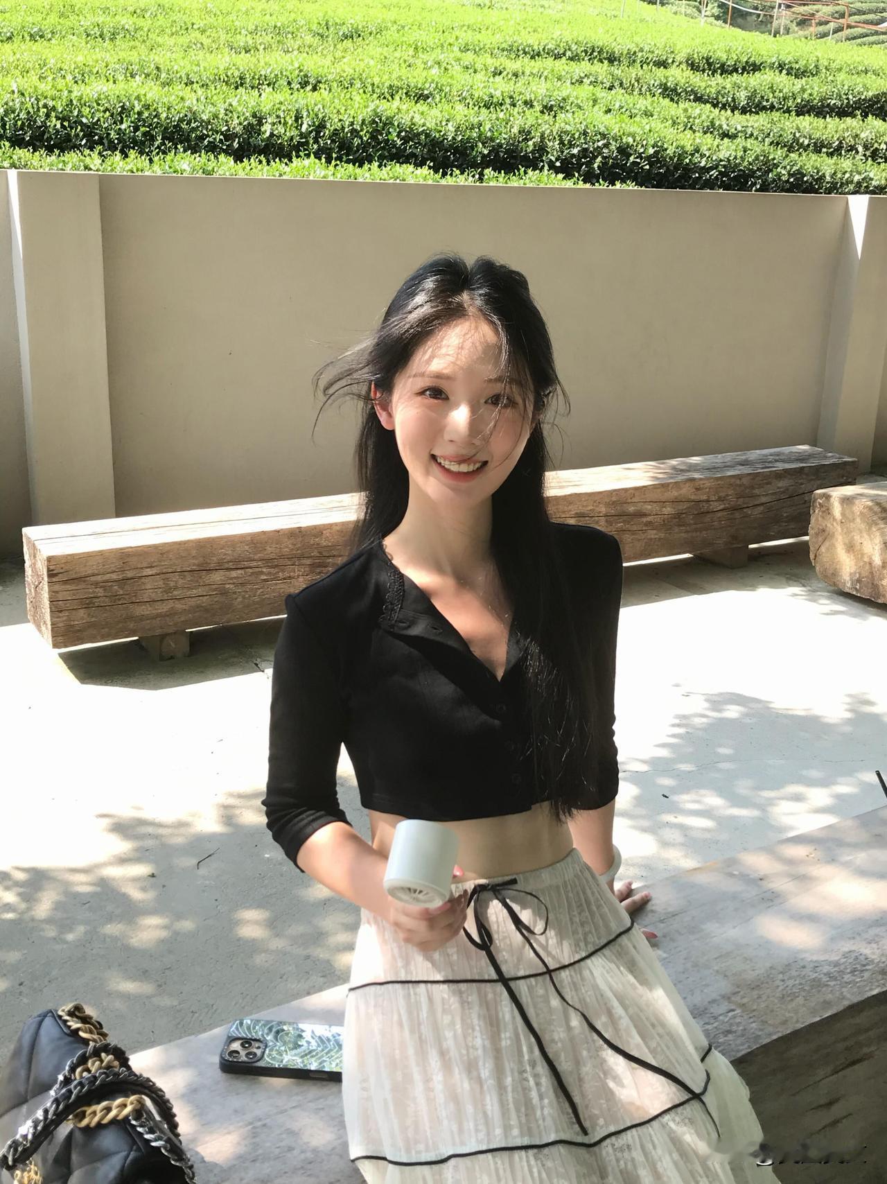 阳光下的茶园美景，与她优雅的笑容相映成趣。