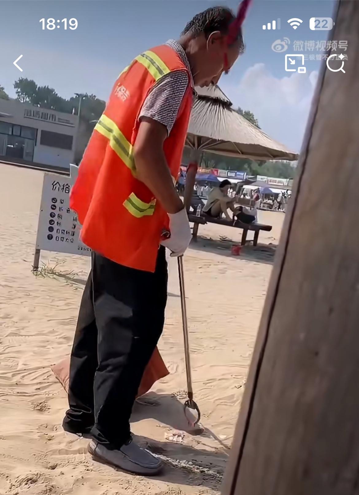 沙滩上一环卫工人把垃圾塞进沙子里，再用脚把它抹平。这样海滩上面就没有垃圾了，这名