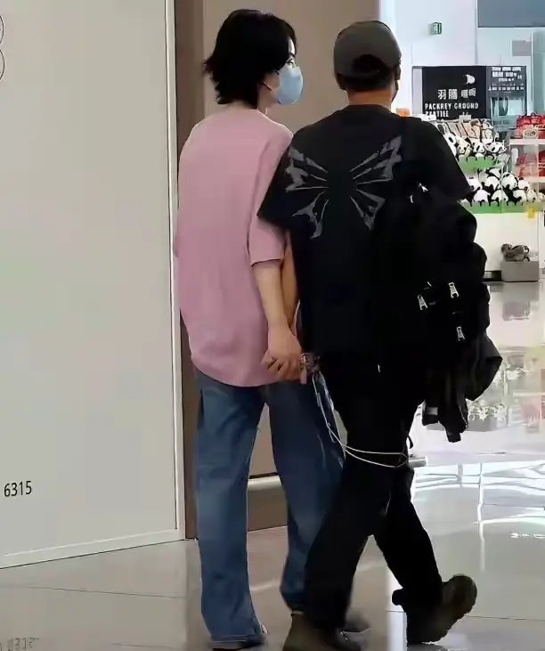 王菲和谢霆锋离开西安，两人十指相连很甜，王菲穿粉色宽T恤很美