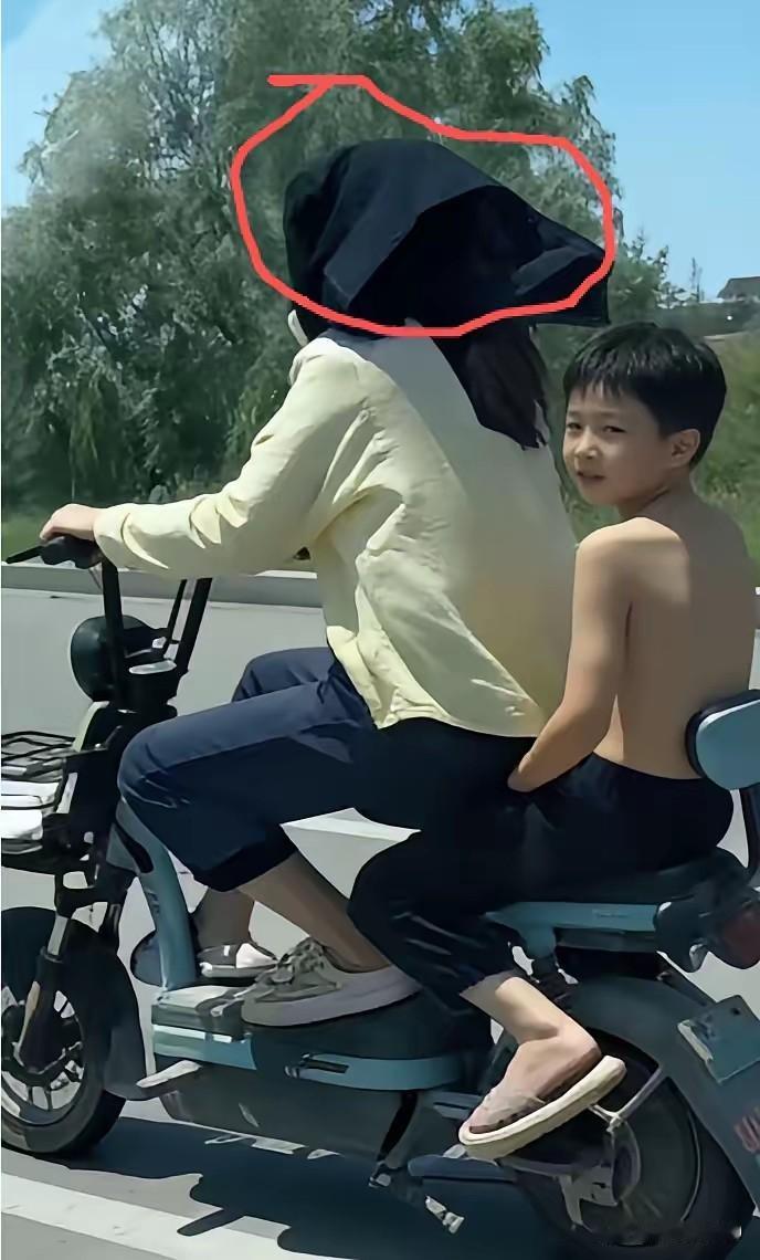 这个聪明妈妈这两天彻底火了。天太热没带伞，直接把儿子衣服扒光了当遮阳帽。后座