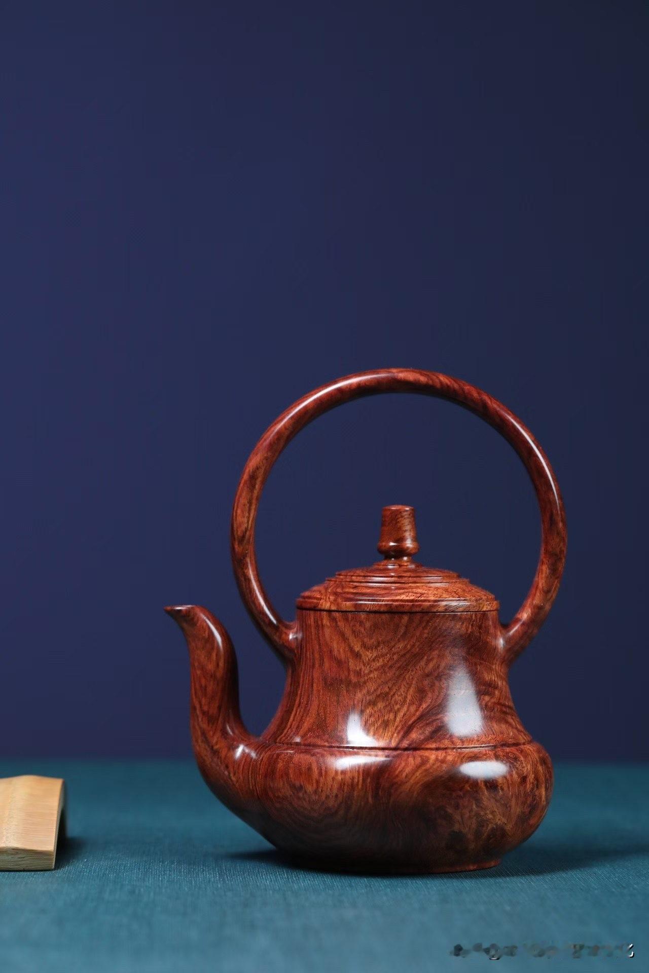 这把提梁壶，不只是器，是一段被收住的水。黄花梨瘿子料的纹理，像山川回转，黑