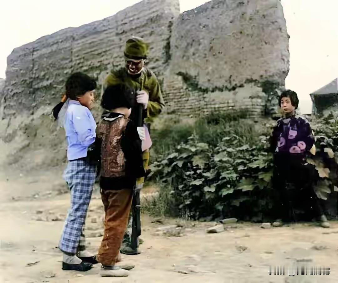 这个日本鬼子一手握着拄在地上的枪，假惺惺的在和两个小女孩说着什么，另一个女孩站的