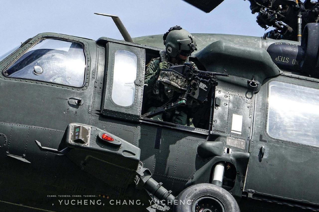 伪台陆军UH-60M“黑鹰”通用直升机舱门机枪手，整个上半身都得露在直升机外。