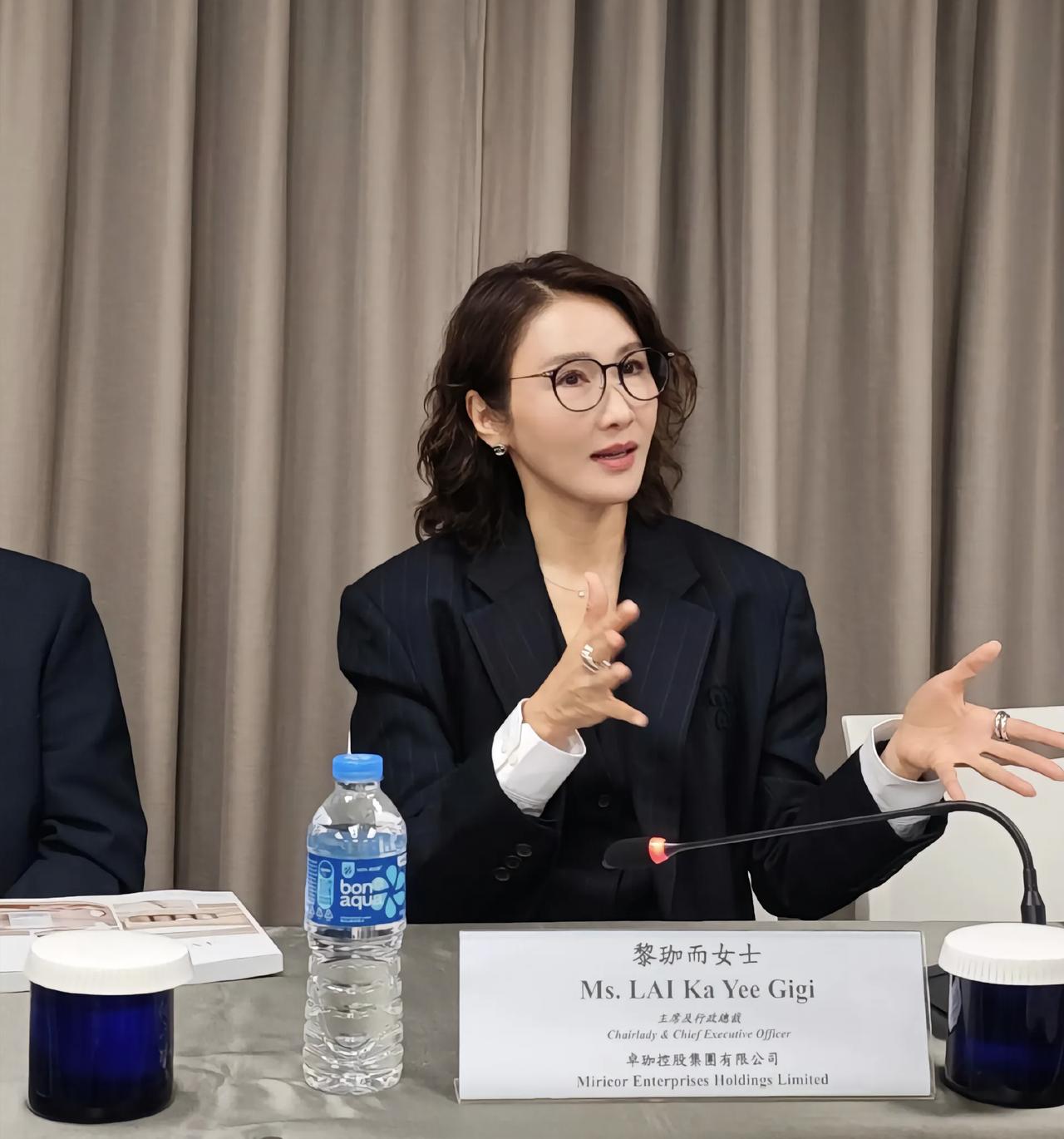 54岁黎姿参加公司董事会议，她的名牌上标着原名“黎珈而”。她的穿衣打扮很强势，一