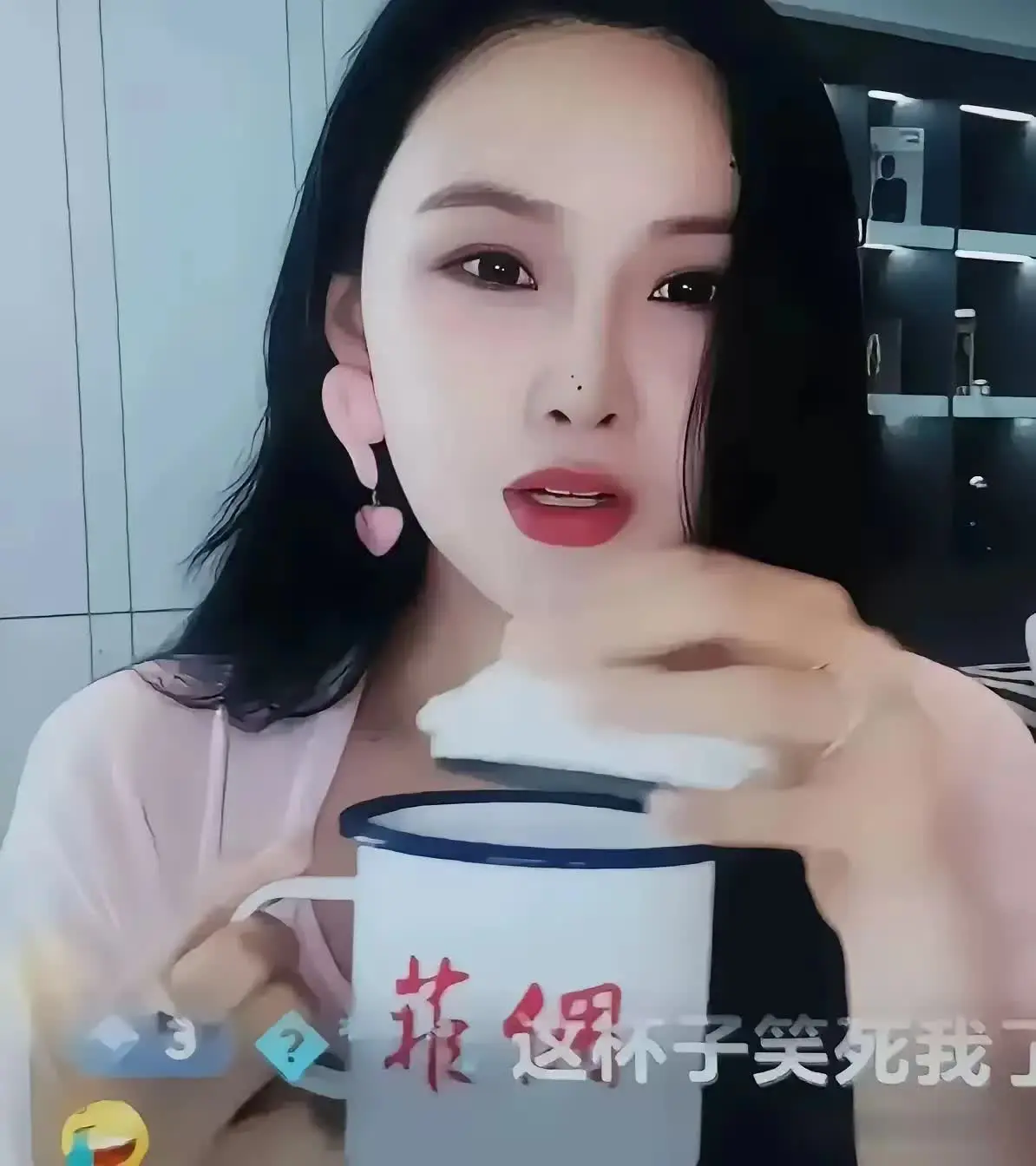 张颖颖在直播间拿着个茶缸，慢悠悠地喝着茶。茶缸外侧分别贴着“澳星Q梅”、“菲
