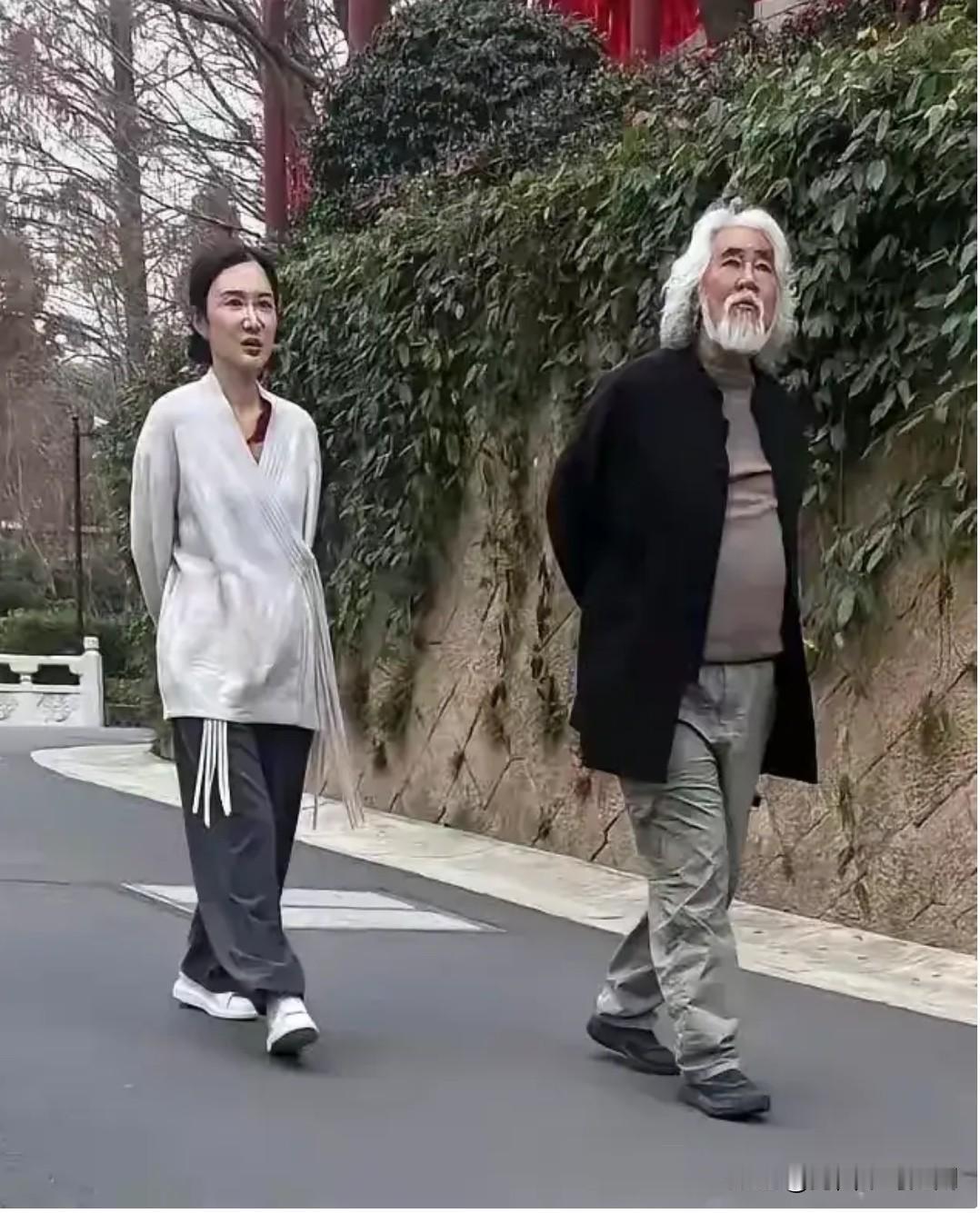 这是张纪中与小娇妻杜星霖一起散步的一张留影。张纪中白发长须，仰首挺胸、气度从容走