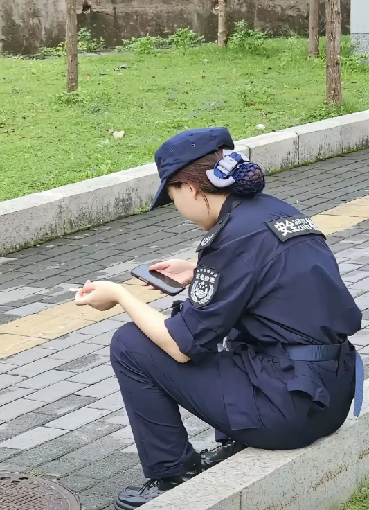 湖南，有一名男子乘坐地铁回家，在地铁出口看到一名女保安坐在草坪前玩手机，左手上还