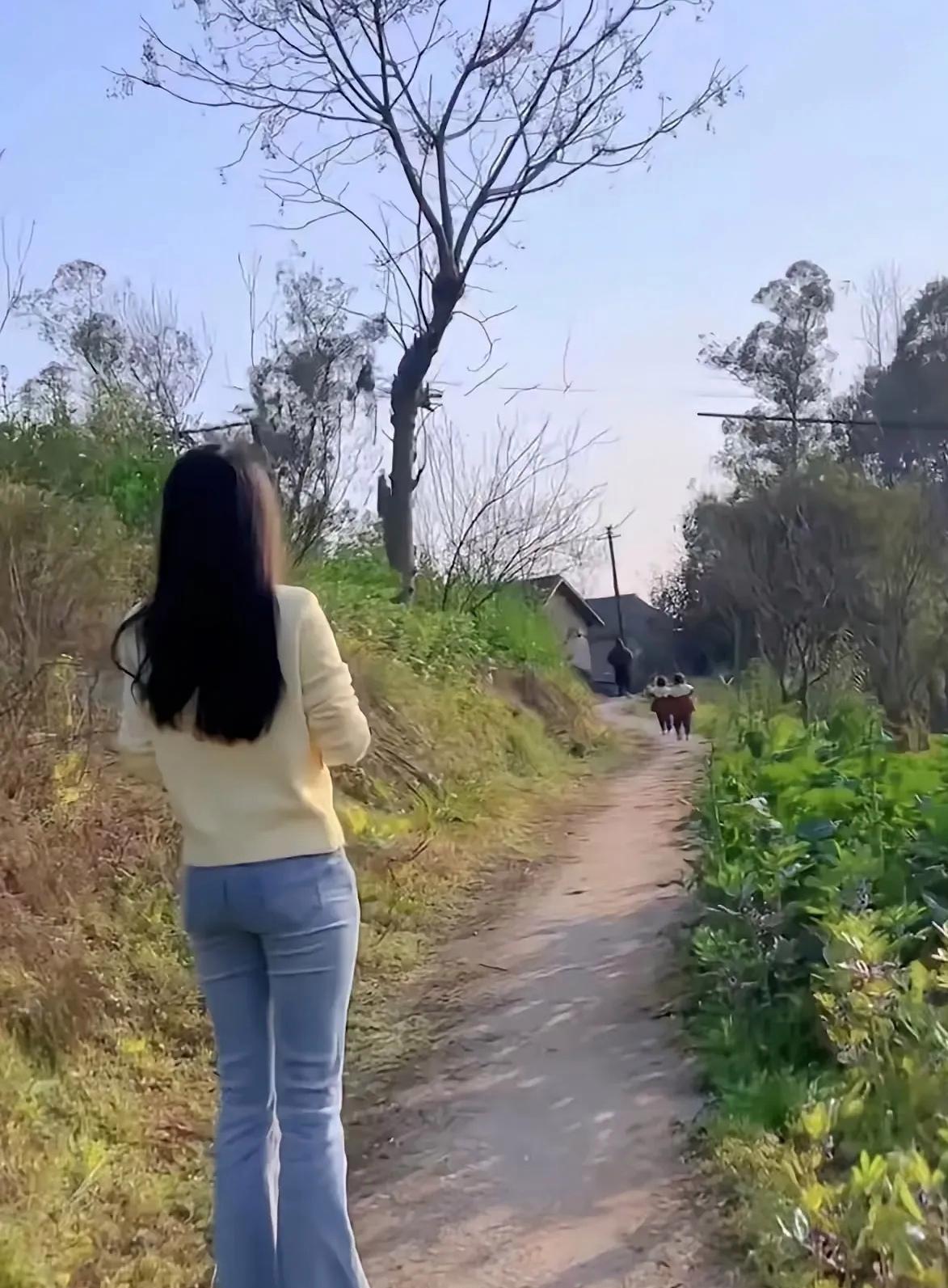 一个人站在乡间小路上，看着远处的风景，心情愉悦。