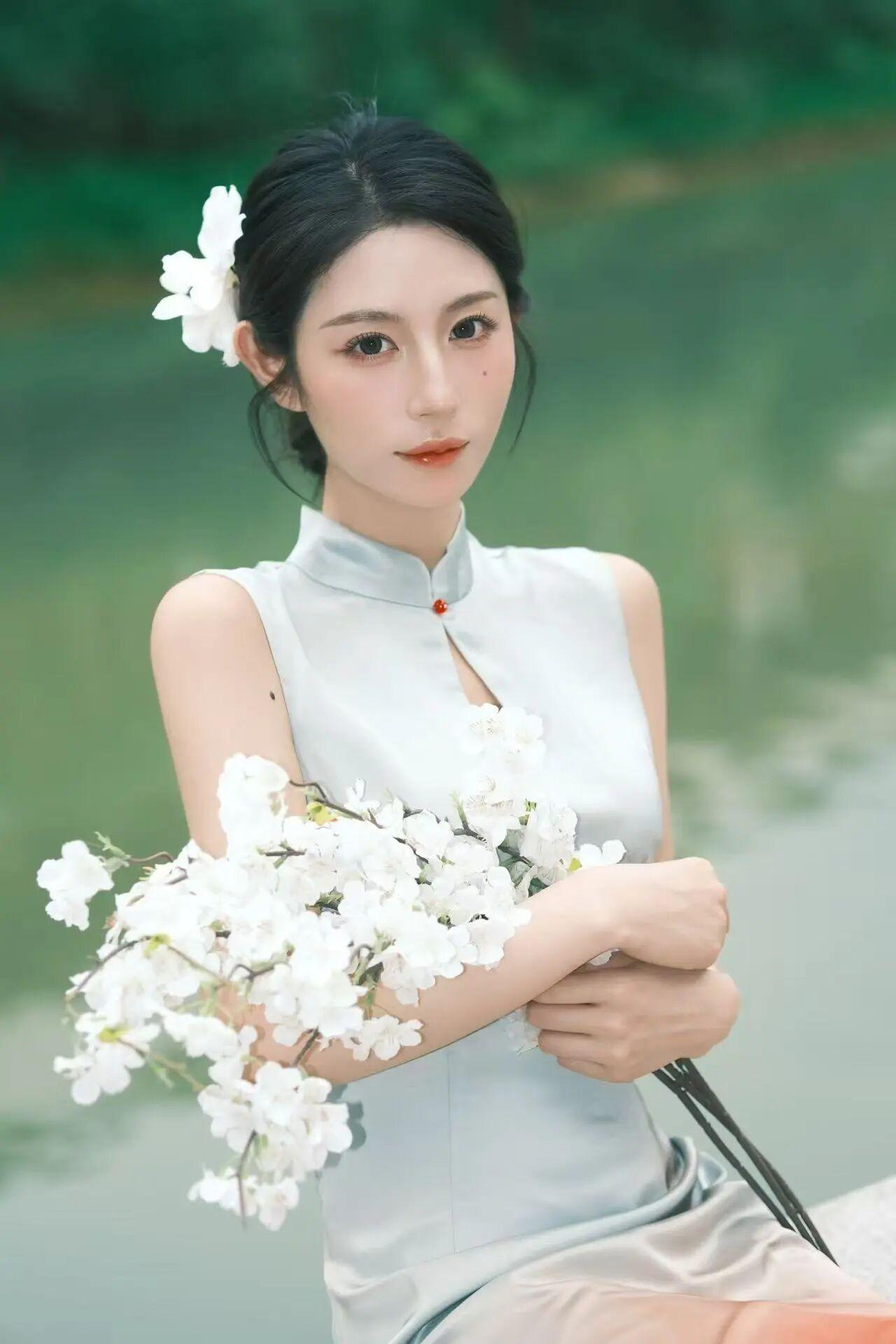 清新脱俗的汉服少女，手持一束白花，静坐湖畔，宛如画中人。