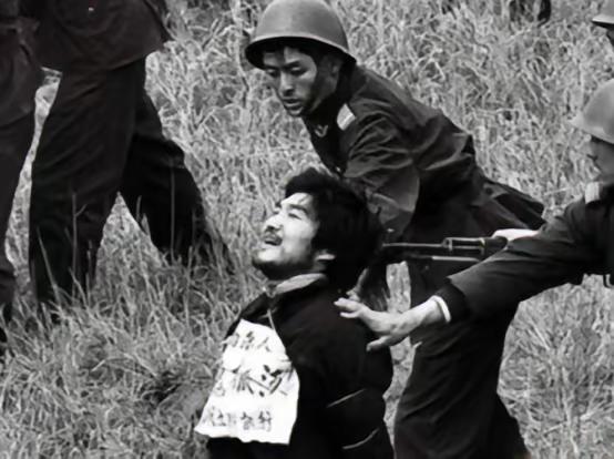 1990年，这是即将枪决西北悍匪魏振海的现场，他被五花大绑地，双膝跪在草丛中，满