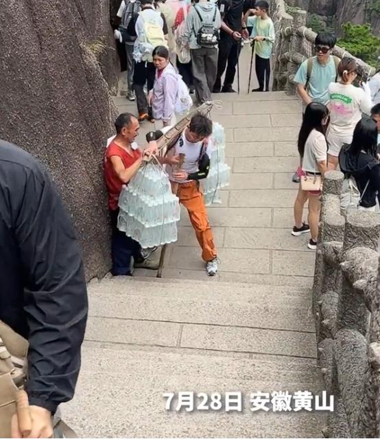 7月28日，在安徽黄山，一名90后小伙登山途中碰到一位挑山工，对方肩上的扁担两端