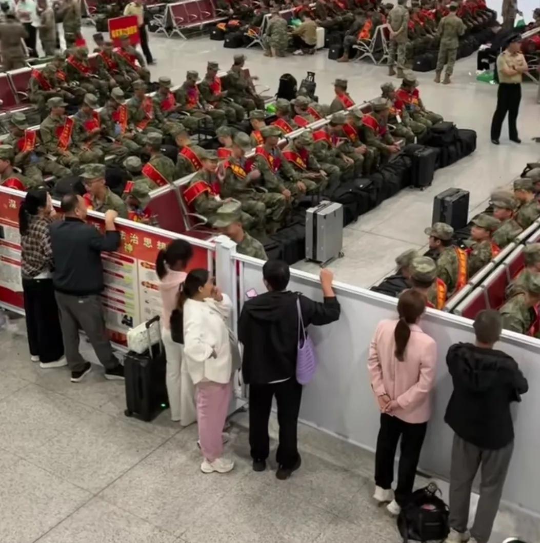 南阳东站众家属举目隔板送亲人入伍候车。