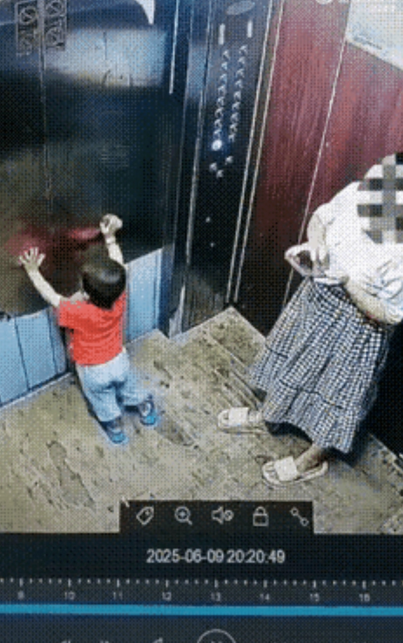 母子乘坐电梯回家。在电梯里，孩子的妈妈低头玩着手机，孩子独自在电梯门旁，小手不停
