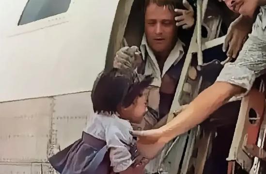 越战结束，一位越南母亲带着两个孩子送美国撤军的一名士兵时的一张照片。照片中的妇女