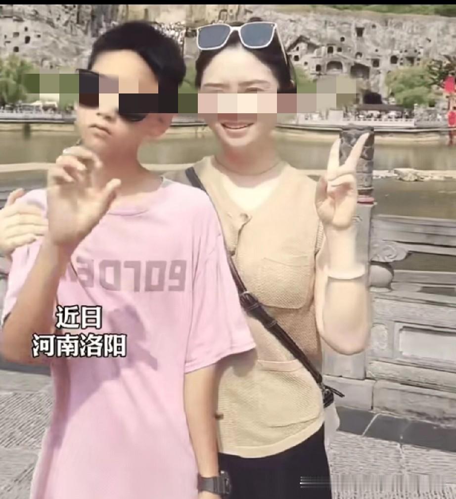 万万没想到。河南洛阳，妈妈强拉儿子一起拍照，妈妈比出耶的手势，本以为儿子也会配合