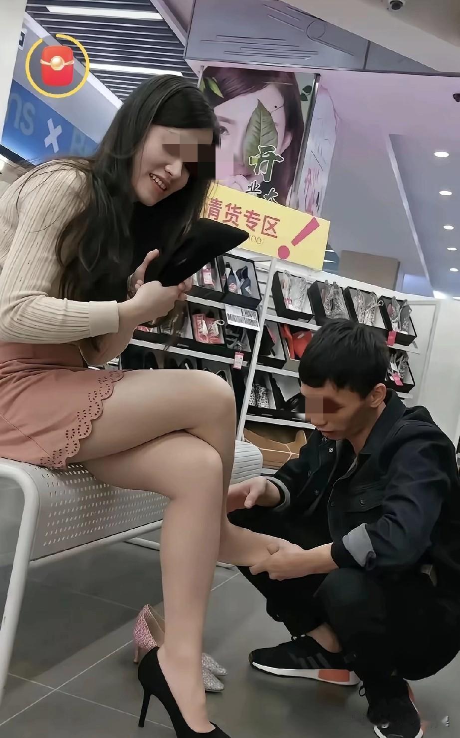一对情侣在商场试穿鞋子，女子正在试穿一双高跟鞋，👠重点来了，是男子用双手躲在地