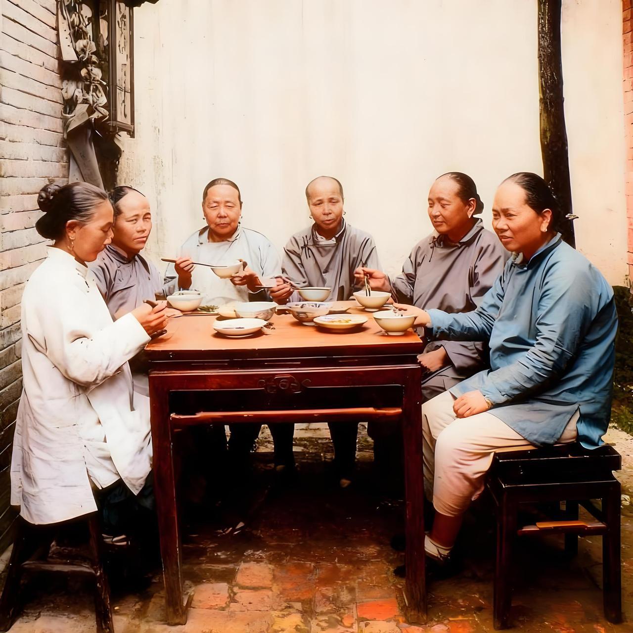 这是一张拍摄于一百多年前杭州的老照片，记录了当地一户地主家女眷用餐的场景。画面中