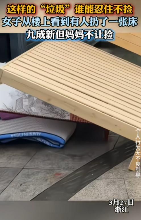 九成新的床扔到垃圾旁，女子想捡，但妈妈不让捡。还是实木床，看着很新，很让人心动。