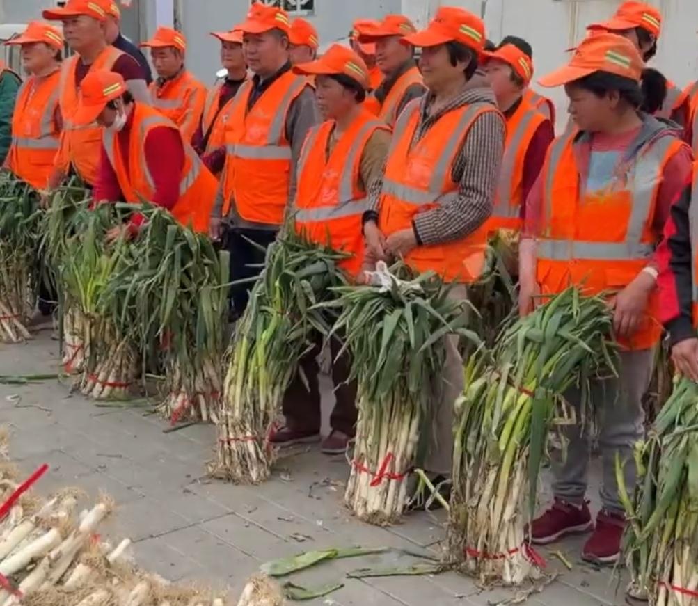2026年3月27日早上，河南某菜市场。大葱摊前，几名环卫工人围着摊主说话。