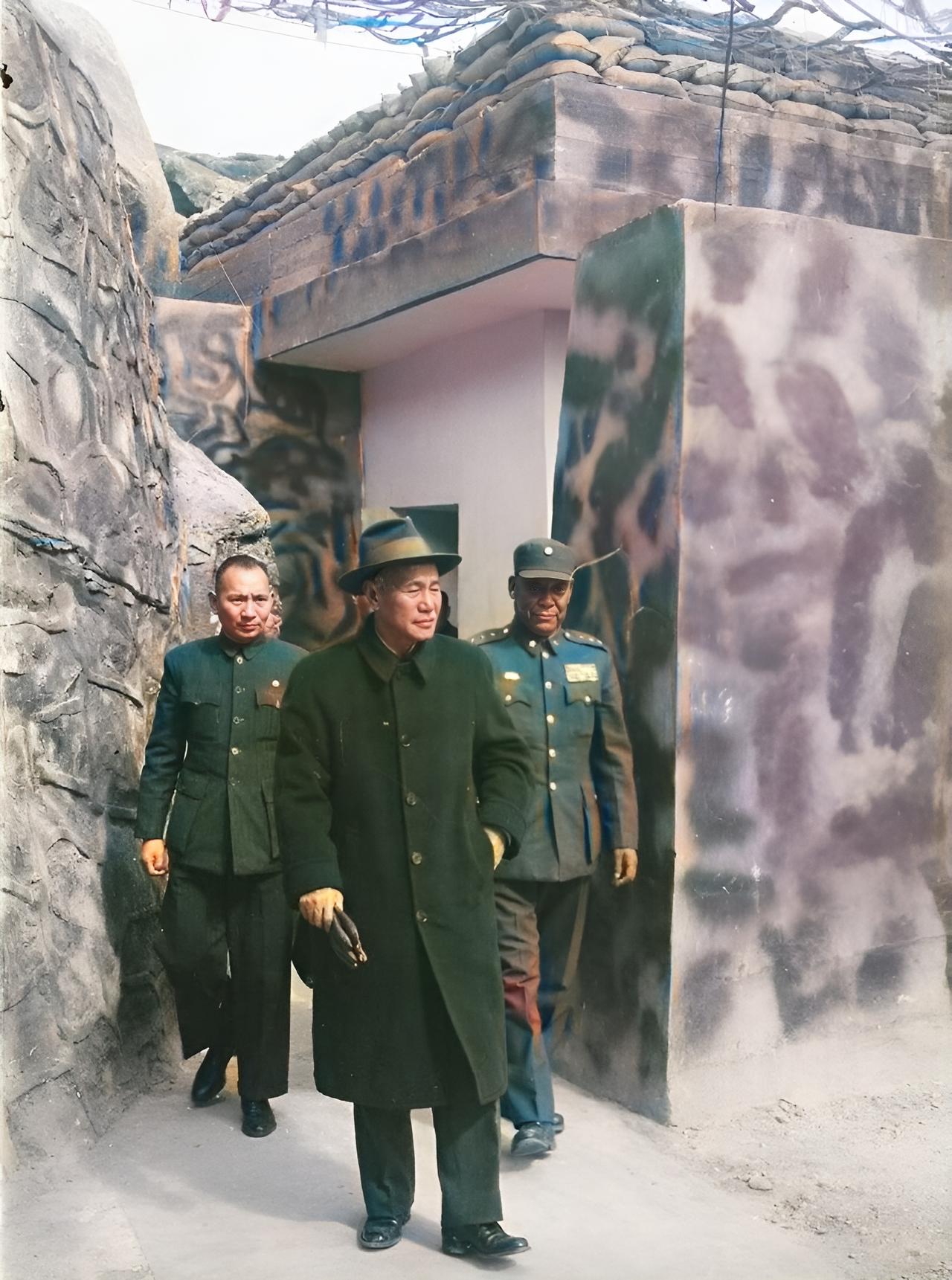 这是1959年蒋中正到金门岛视察前线战地工事。他头戴礼帽，身穿长款呢大衣，左手插