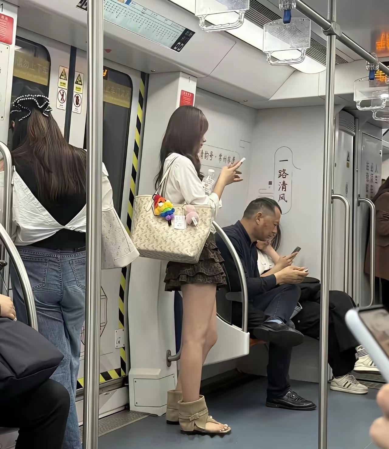 地铁里站着个穿短裙的妹子。