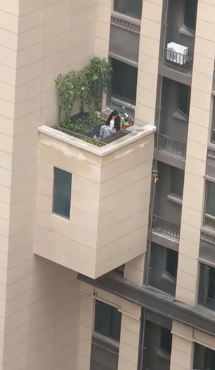 刚才拍到的，我腿都软了...对面楼21层，这姑娘居然坐在外挑平台上晒太阳！没