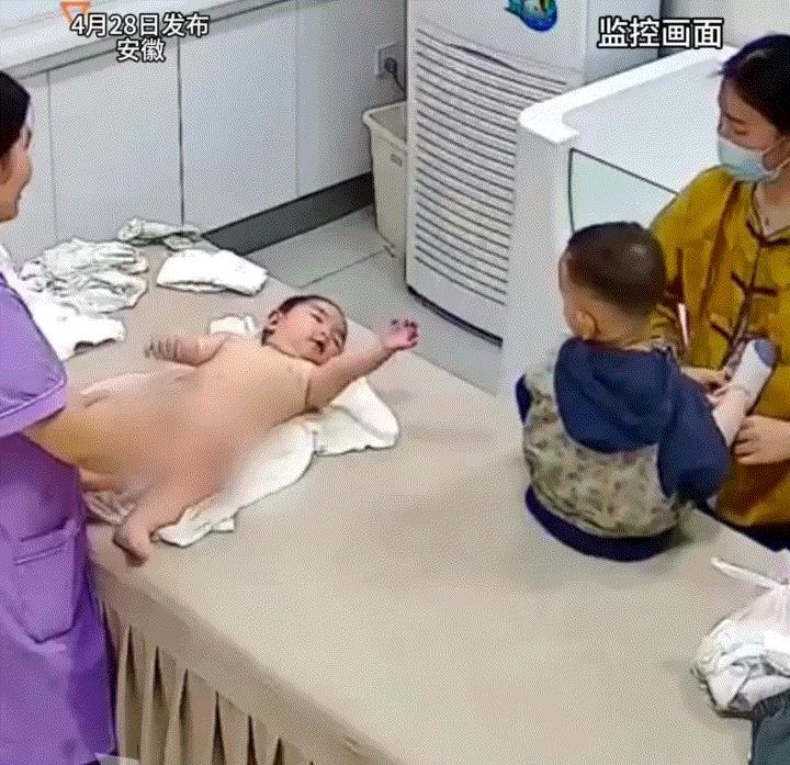 一宝宝洗完澡后等待擦干身体，不料旁边的另一位小孩突然用手朝着小宝宝的脸上就是一巴