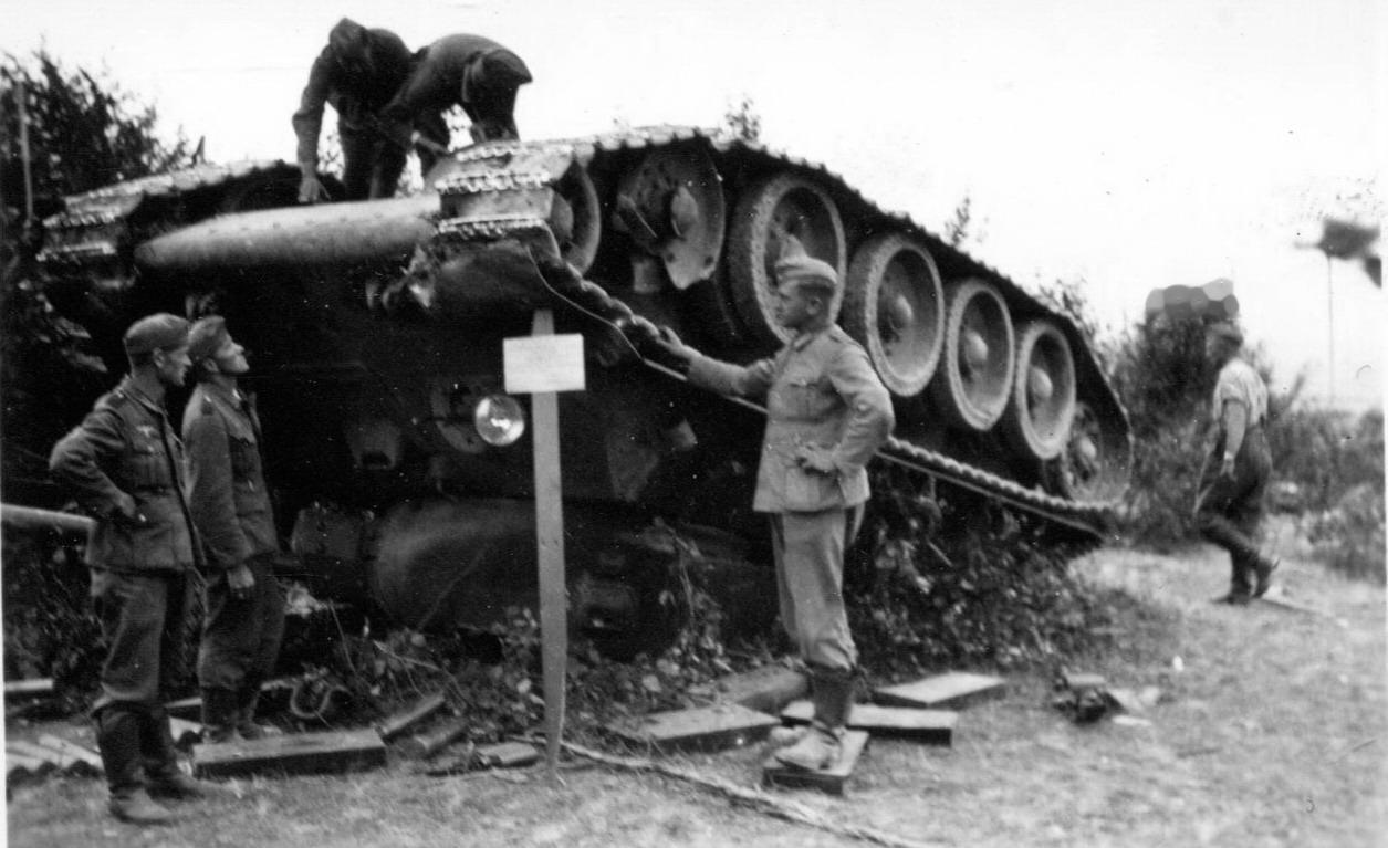 1941年，东线。德军士兵正好奇地查看一辆倾覆的苏军T-34中型坦克。1