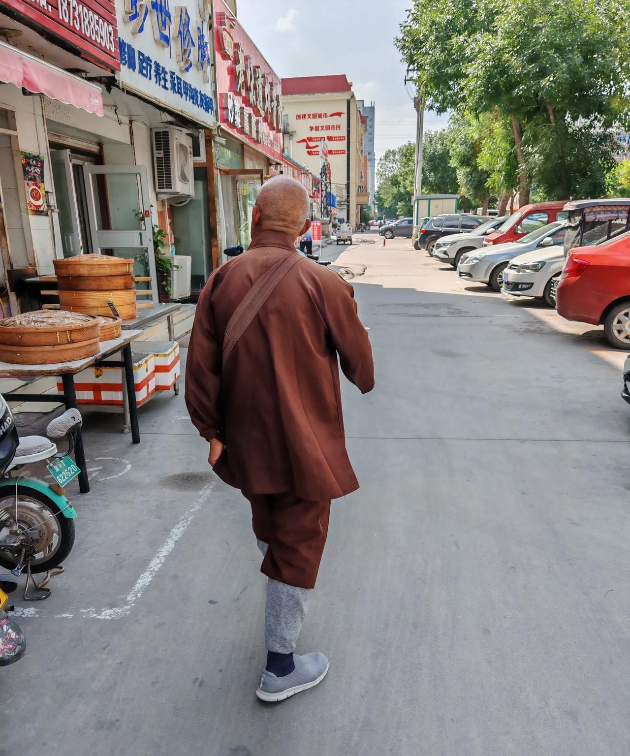 街面上出现了化缘的僧人，这位僧人看上去年事已高。他化缘的方式是挨家店铺进去讨要。