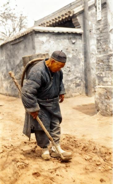 这张照片定格了清末一位街头拾粪老汉的身影，他头戴瓜皮小帽，身着打满补丁的暗沉旧棉