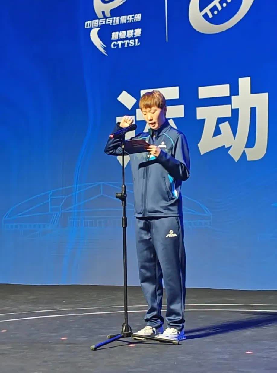 王曼昱作为运动员代表，上台宣誓了，身穿运动衣，板板正正，做着右手握拳的宣誓手势，